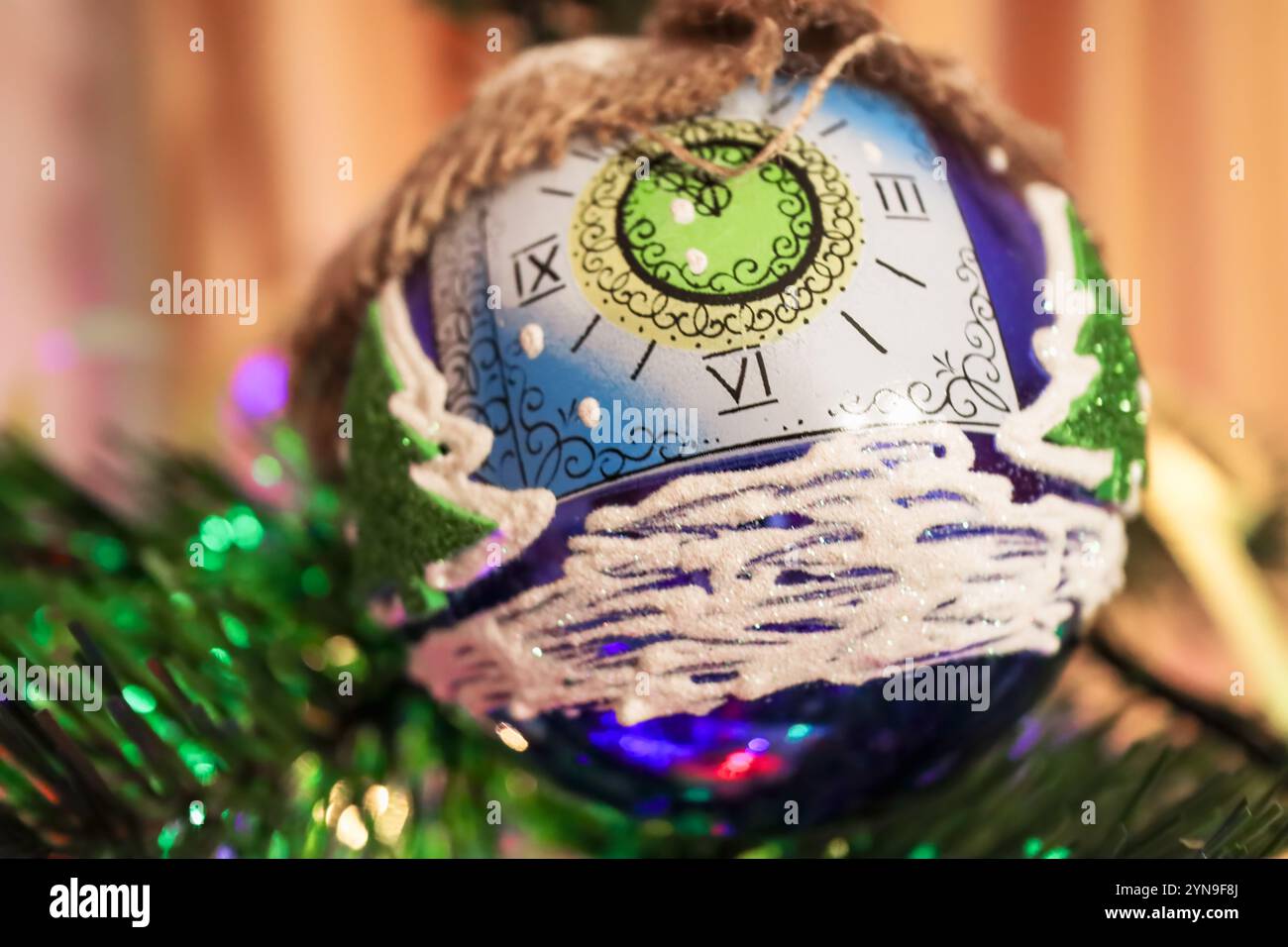 Weihnachtsbaumschmuck. Festlicher blauer Ball in Form einer Uhr mit Mustern aus farbigem Glitzer. Stockfoto