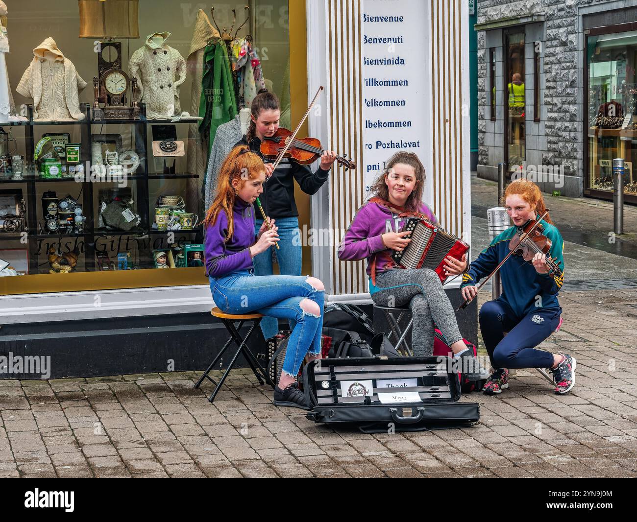 Eine Gruppe junger Musiker tritt auf einer geschäftigen Straße energisch auf. Sie spielen traditionelle Instrumente und verstärken die lebhafte Atmosphäre der Stadt. Die Szene Stockfoto