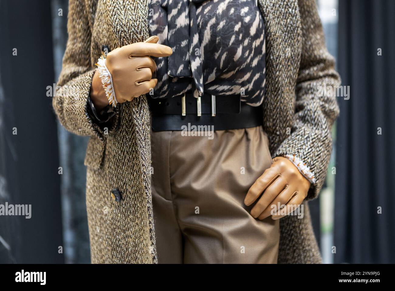 Elegante Fashion Details stilvolles Damen-Outfit beige Lederhandschuhe und -Gürtel, Tweed-Blazer und bedruckte Bluse für trendige Looks in modernen Garderoben, Neut Stockfoto