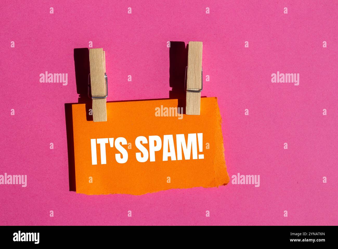 Es ist eine Spam-Nachricht, geschrieben auf zerrissenem orangenem Papierstück mit rosa Hintergrund. Konzeptionell ist das Spam-Symbol. Kopierbereich. Stockfoto