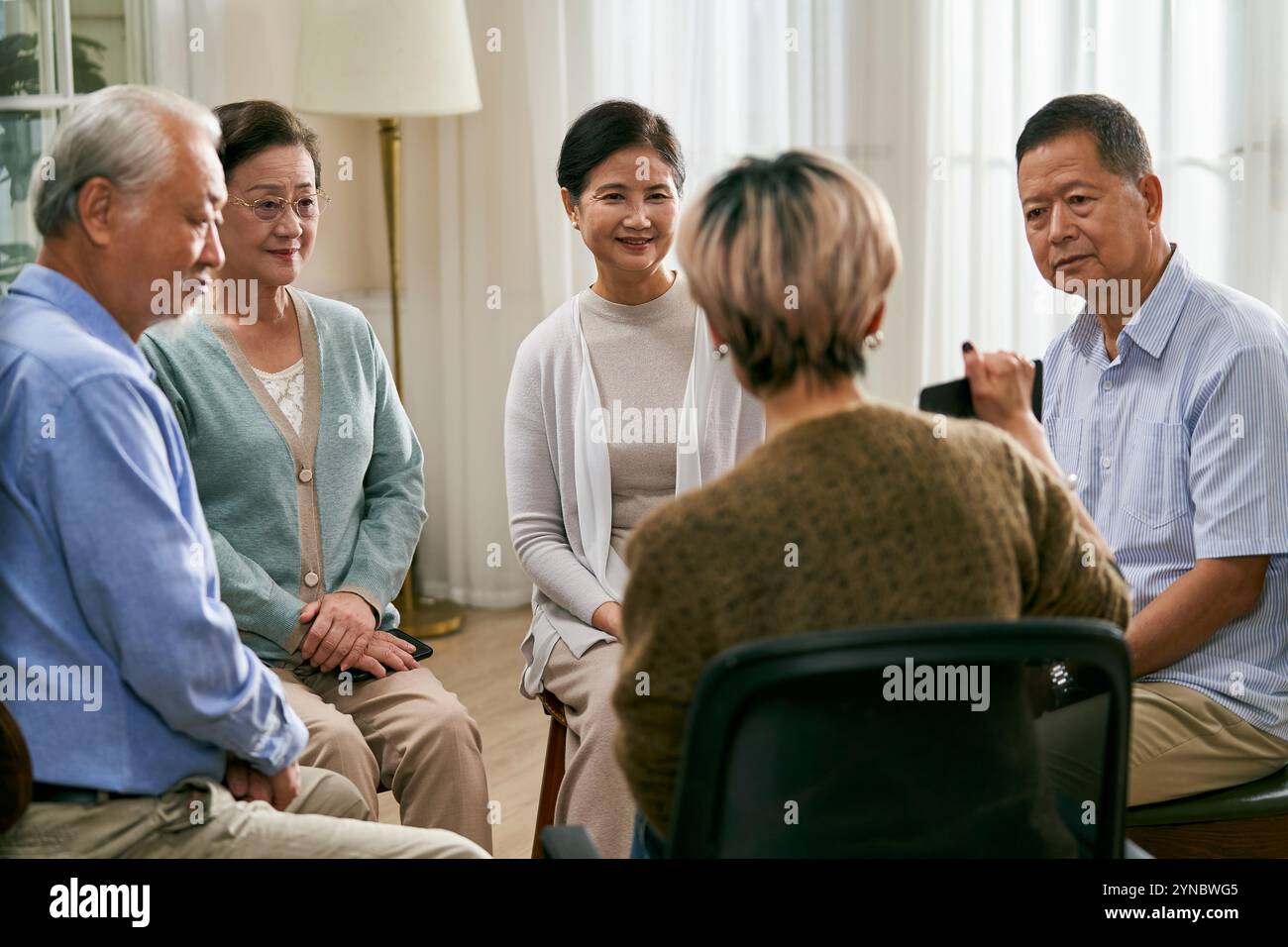 asiatische Beraterin, die eine Diskussionsrunde für eine Gruppe von Senioren leitet Stockfoto