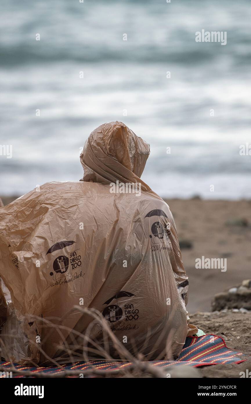 Die Person, die während ihres Urlaubs in Griechenland am Sandstrand saß, entschloss sich, bei jedem Wetter eine gute Zeit zu haben. Stockfoto