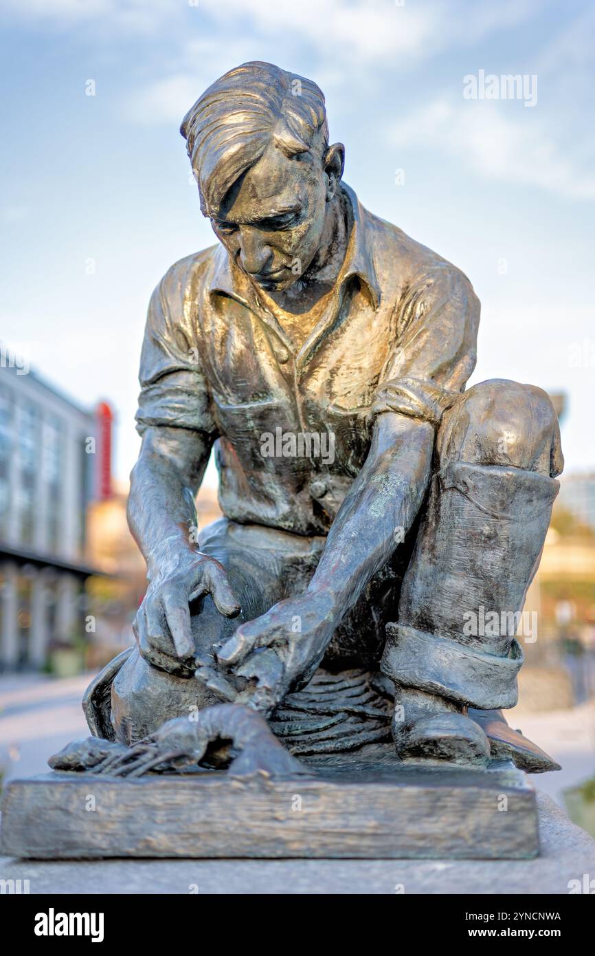 WASHINGTON DC, Vereinigte Staaten – Eine Replik der Maine Lobsterman-Statue von Victor Kahill steht an der Wharf im Südwesten von DC. Die ursprüngliche Bronzeskulptur aus dem Jahr 1939 zeigt den Fischer H. Bailey Wilbert auf Bailey Island in seiner Ölkleidung und demonstriert die traditionelle Methode, Hummerkrallen zu binden. Ein weiterer Abguss der Statue steht in Portland, Maine. Stockfoto