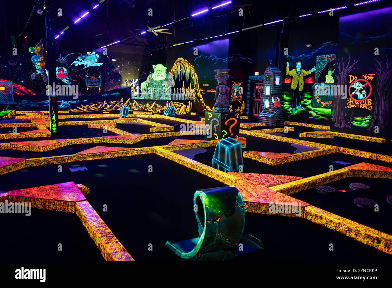 Monster Mini Golf Interior Chantilly Virginia // CHANTILLY, Virginia — das Innere des Monster Mini Golf ist mit leuchtenden UV-reaktiven Dekorationen und Neonkunstwerken ausgestattet, die von Schwarzlichtern im Inneren des Minigolfplatzes beleuchtet werden. Die Anlage kombiniert Elemente im Monsterstil mit fluoreszierenden Farben, um ein immersives Glühen-in-the-Dark-Putting-Erlebnis zu schaffen. Stockfoto