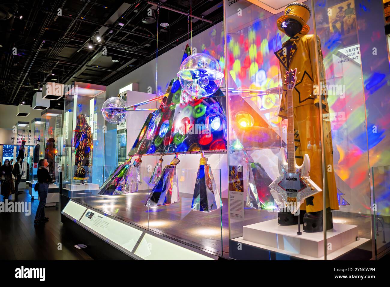 P-Funk Mutterschiff Bootsy Collins Ausstellung Washington DC // WASHINGTON DC — das berühmte P-Funk Mutterschiff und Bootsy Collins' unverkennbare Aufführungsartikel sind im National Museum of African American History and Culture ausgestellt. Die Ausstellung zeigt Collins’ charakteristischen gelben Bühnenanzug neben seiner Bassgitarre, die Schlüsselelemente der Funk-Musikgeschichte repräsentiert. Diese Artefakte zeigen die theatralischen und musikalischen Elemente, die die bahnbrechenden Aufführungen von Parliament-Funkadelic prägten. Stockfoto