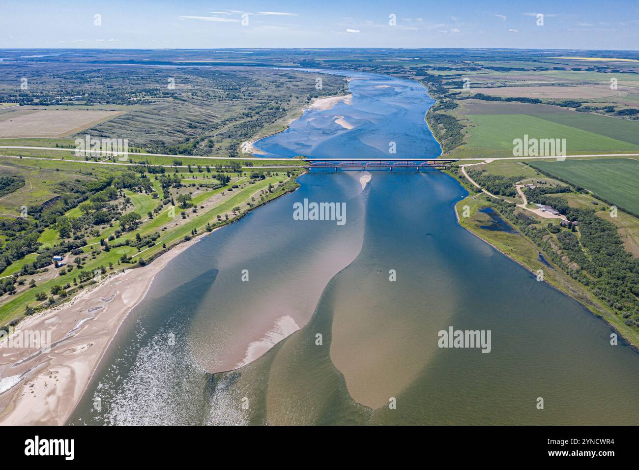 Ein großes Gewässer mit einer Brücke darüber. Das Wasser ist braun und die Brücke weiß Stockfoto