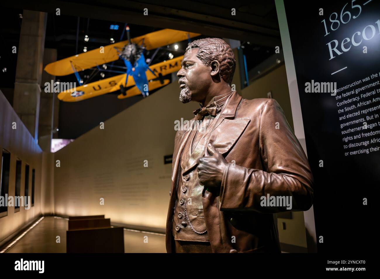 National Museum of African American History Robert Smalls Statue Washington DC // WASHINGTON DC – das National Museum of African American History and Culture zeigt eine Bronzestatue von Robert Smalls, dem versklavten Piloten, der ein Schiff der Konföderierten in die Freiheit kommandierte und später als US-Kongressabgeordneter diente. Über der Statue hängt ein restauriertes PT-13D Stearman Kaydet Trainingsflugzeug, das von den Tuskegee Airmen, Amerikas ersten schwarzen Militärpiloten, eingesetzt wurde. Das Flugzeug, das von Captain Matt Quy restauriert wurde, trägt Unterschriften von Original Tuskegee Airmen auf seiner unteren Tür. Stockfoto
