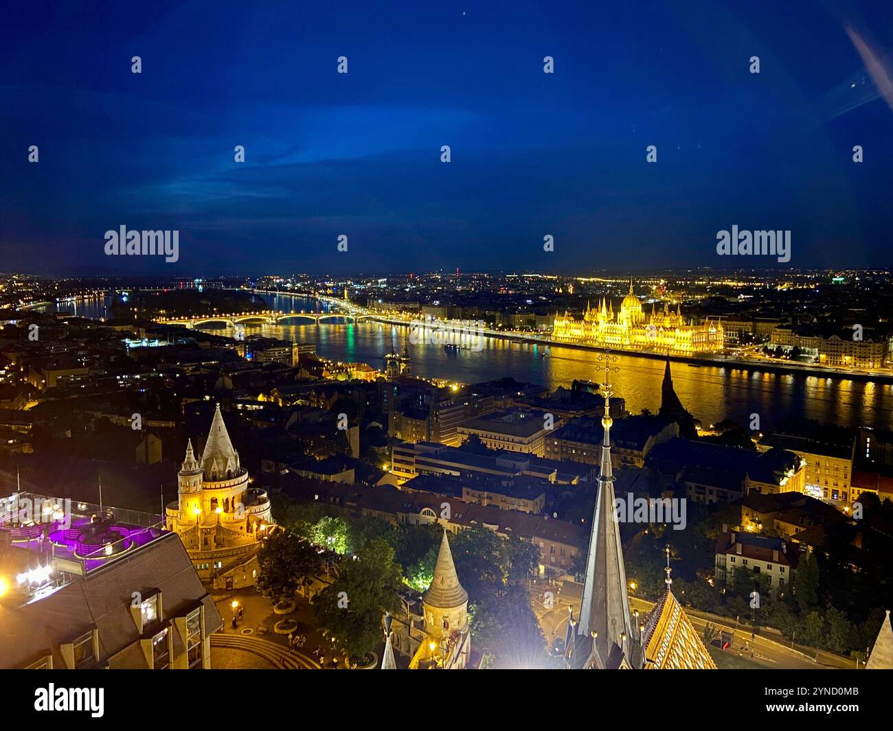 Atemberaubender nächtlicher Blick auf Budapest mit Blick auf das beleuchtete Parlamentsgebäude und die glitzernden Reflexionen auf der Donau. - Smartphone-aufgenommenes Stockfoto