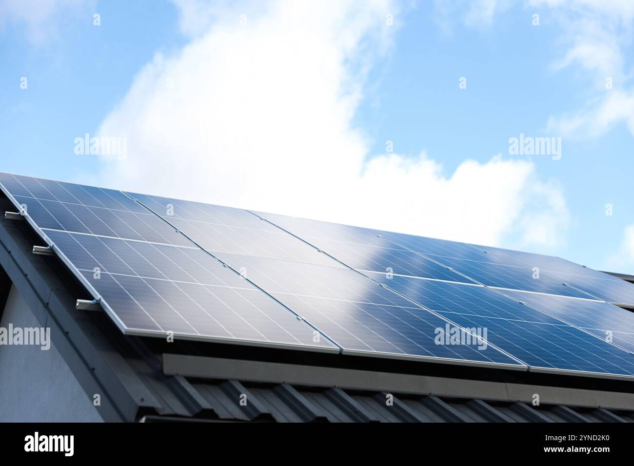 Solarzellen auf wolkenblauem Himmel Hintergrund. Sauberes Konzept für alternative Energie. Modernes Haus mit Solarpaneelen, eigenständige Photovoltaikanlage Stockfoto
