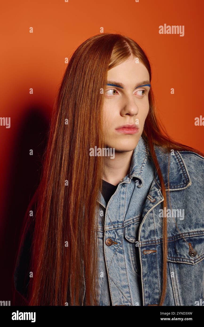 Ein junger Mann mit langen roten Haaren drückt tiefe Emotionen aus, während er selbstbewusst steht. Stockfoto