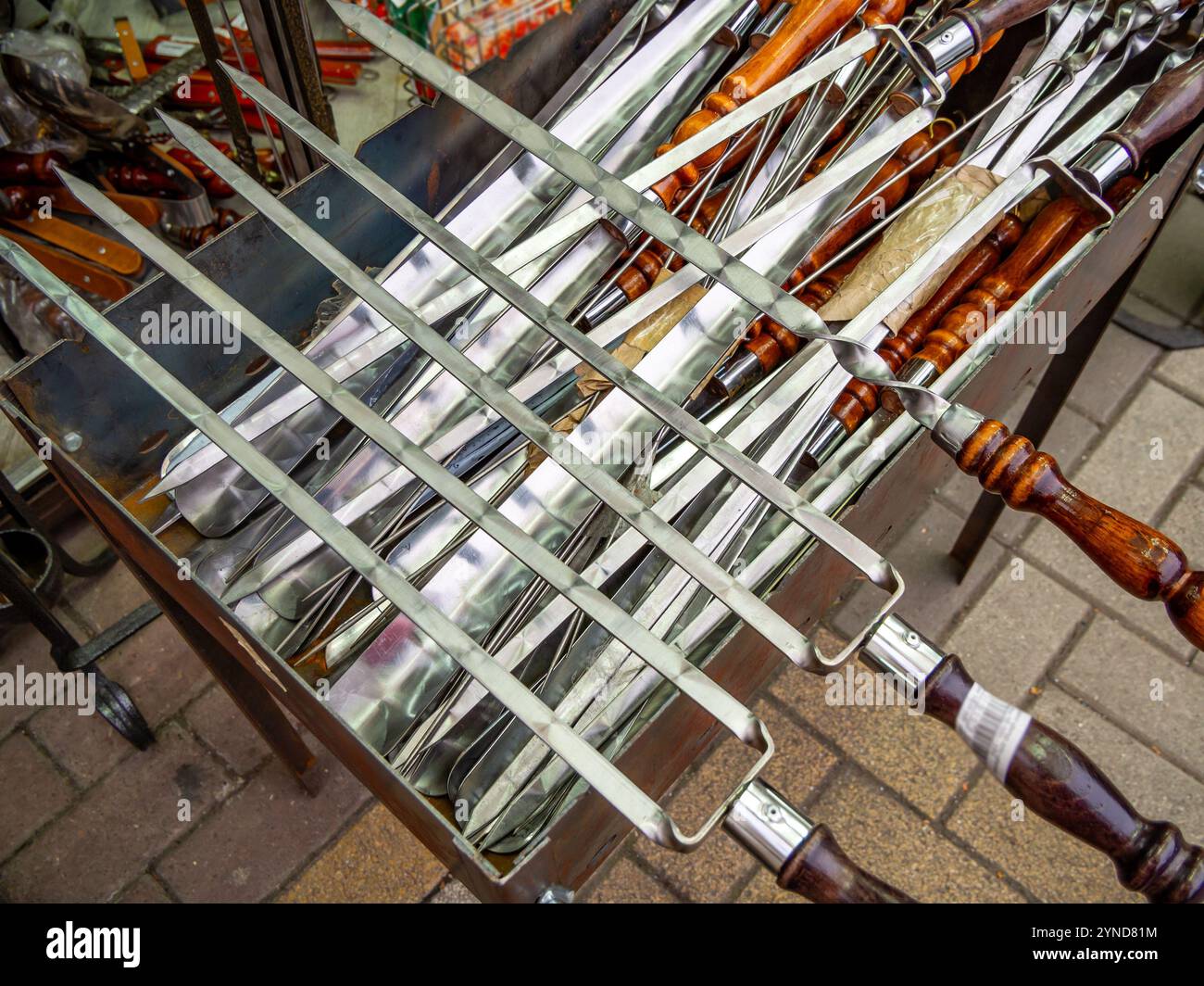 Verschiedene Metallspieße liegen auf dem Grill Stockfoto
