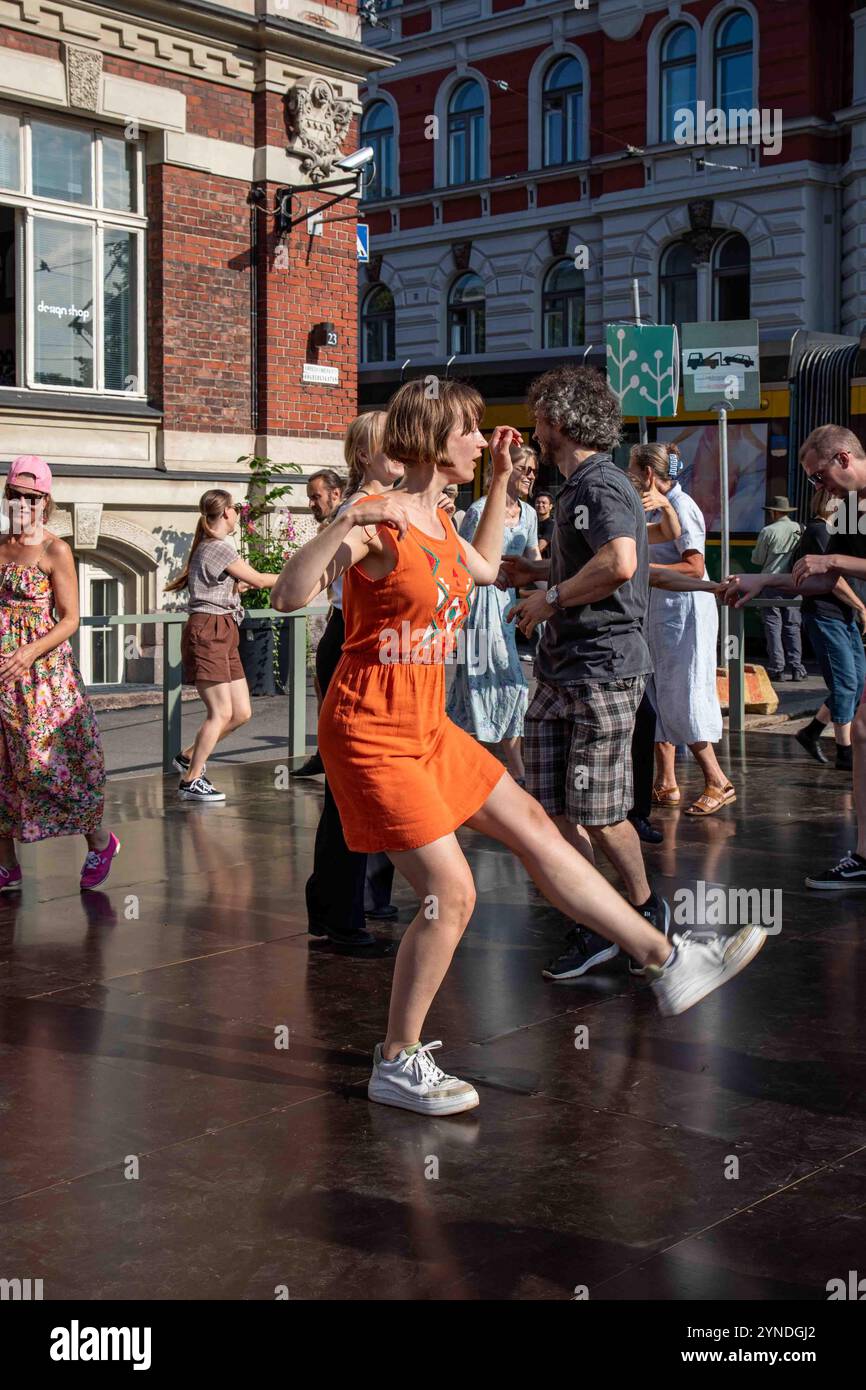 Eine Frau in orangefarbenem Kleid tanzt allein bei Summer Streets Stage Dances im Stadtteil Ullanlinna in Helsinki, Finnland Stockfoto