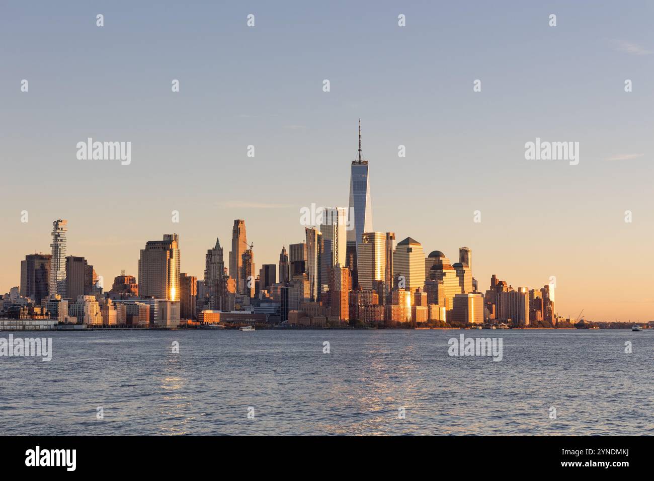 Der südliche Teil der Skyline von Manhattan bei Sonnenuntergang. Wolkenkratzer erzeugen eine auffällige Silhouette mit goldenen Reflexen, die das urbane Leben zum Ausdruck bringen. Stockfoto