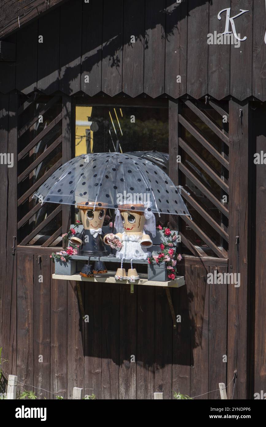 Hochzeitspaar aus Blumentöpfen, sitzt unter einem Schirm in einem Gartenhaus, Franken, Bayern, Deutschland, Europa Stockfoto