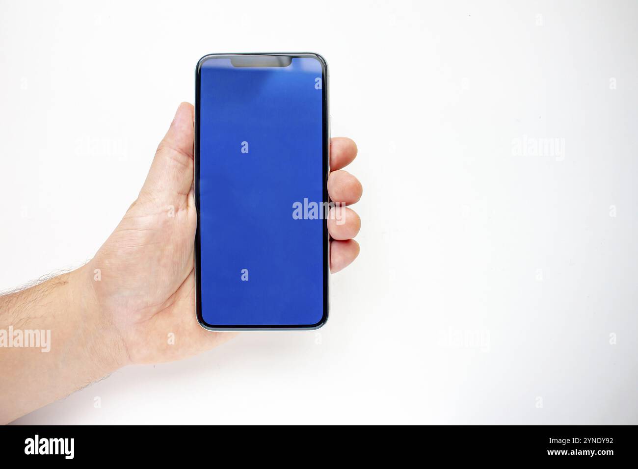 Eine Person, die ein Smartphone mit blauem Bildschirm auf weißem Hintergrund hält Stockfoto