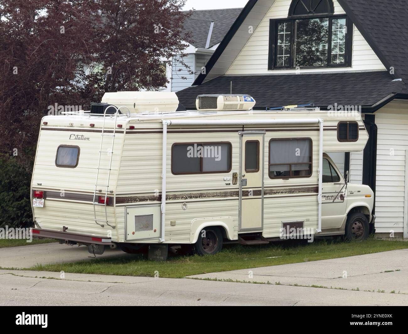 Calgary, Alberta, Kanada. Juli 2024. Ein weißer Wohnmobil parkt auf einer Wohnstraße vor einem weißen Haus. Der Wohnmobil ist ein Ford-Modell der E-Serie Stockfoto