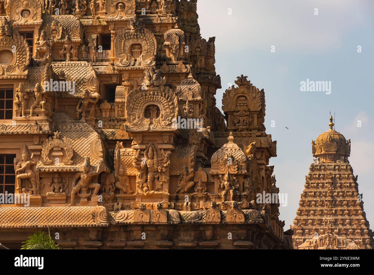 Nahaufnahme komplizierter Schnitzereien auf dem ersten Gopuram von Tanjai Periya Koil, die die künstlerische Exzellenz der Chola-Architektur hervorheben, mit dem Hauptgopuram Stockfoto