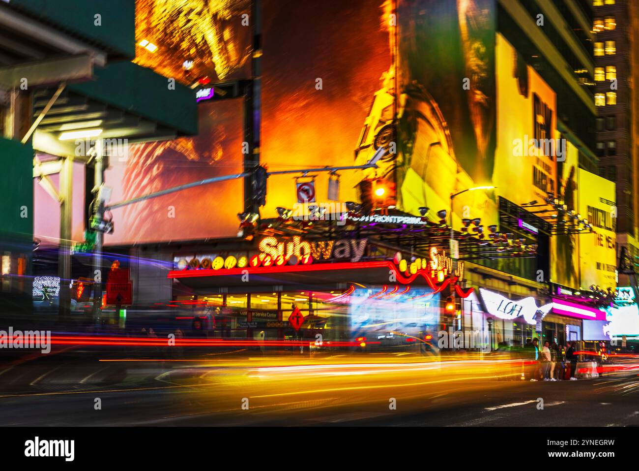 Der Times Square ist bei Nacht mit verschwommenen Lichtspuren von fahrenden Fahrzeugen und leuchtenden Neonschildern im Hintergrund beleuchtet. New York. USA. Stockfoto