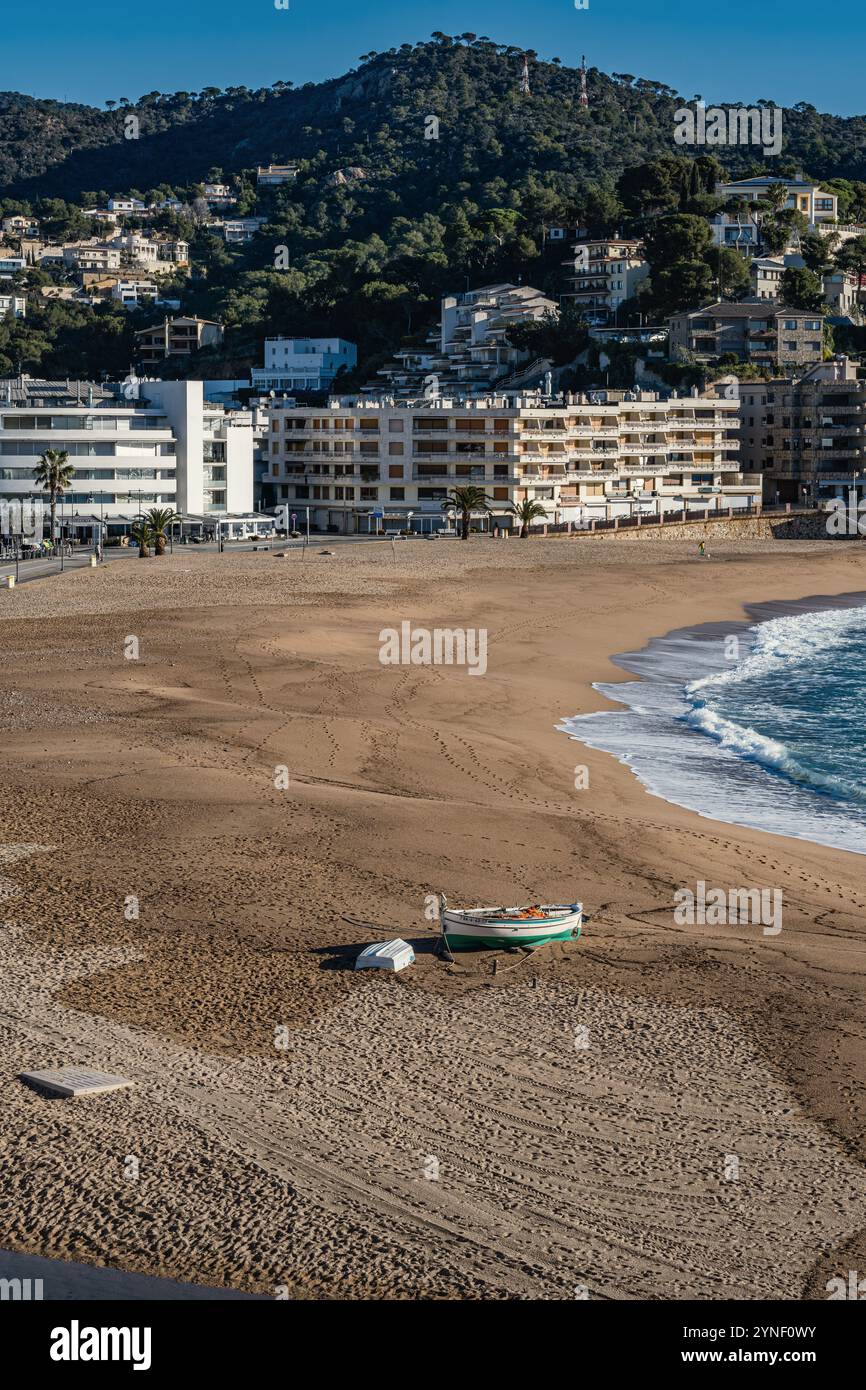 Costa Brava Strand in Spanien, Blick außerhalb der Saison auf Platja Gran in Tossa de Mar. Ruderboote am einsamen Strand und urbane Landschaft im Hintergrund. Stockfoto