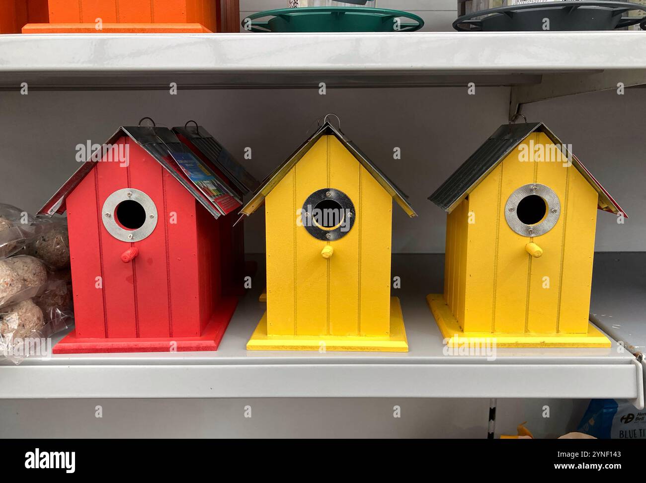 Farbenfrohe gelbe und rote Nistkästen aus Holz zum Verkauf im lokalen Garden Centre - Smartphone-aufgenommenes Stockfoto