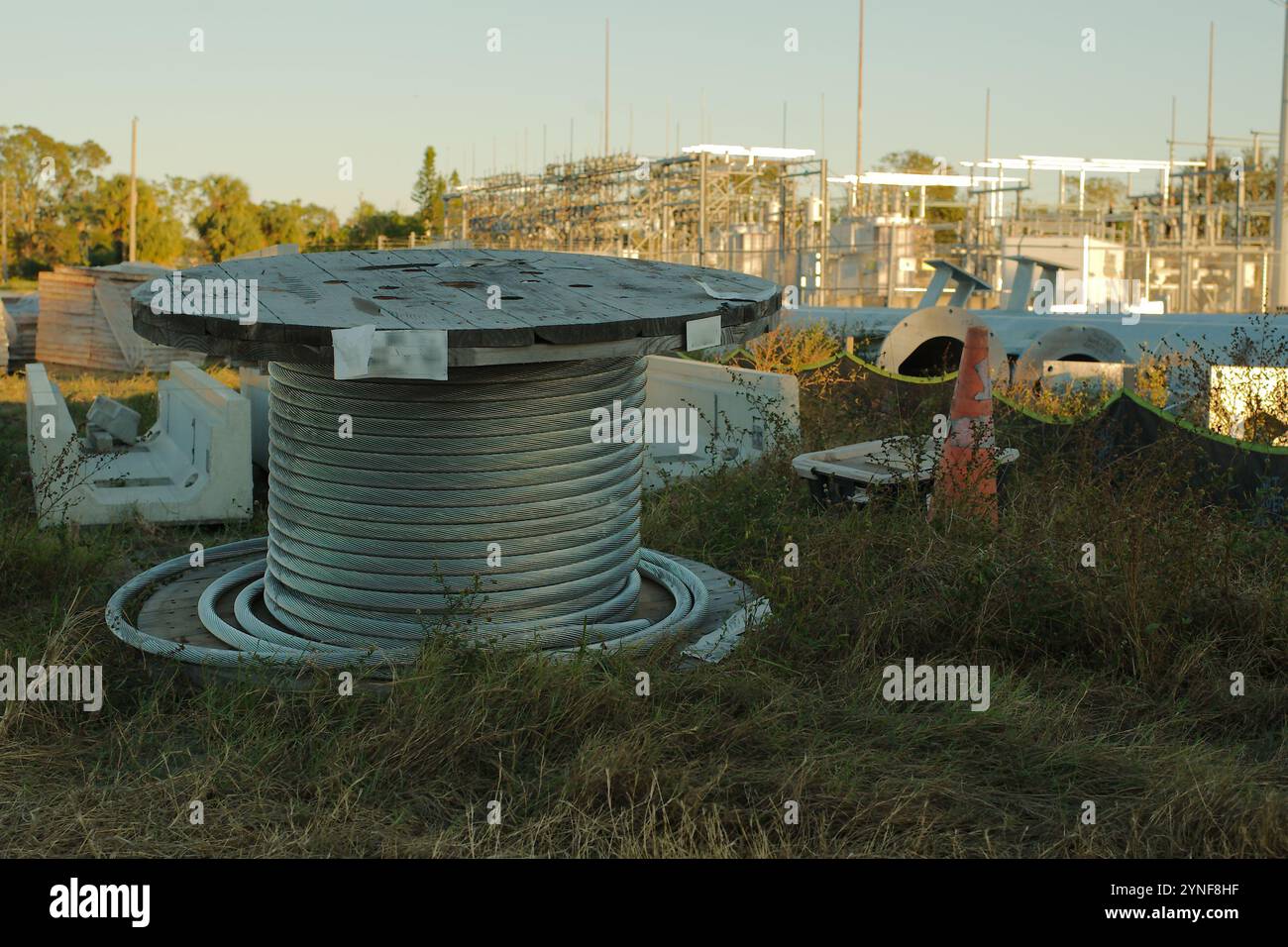 Große Drahtspule aus Holz auf dem Boden in einer elektrischen Umspannstation in der Nähe von Sunset in Florida andere Materialien, Stangen grünes Gras hinten Stockfoto