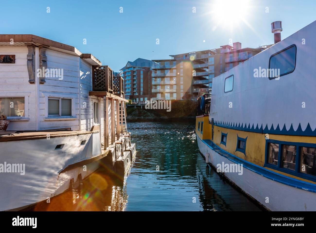 Zwei Boote schwimmen in einem Fluss, von denen eines gelb und blau ist. Die andere ist weiß. Die Sonne scheint hell und schafft ein warmes und einladendes Ambiente Stockfoto