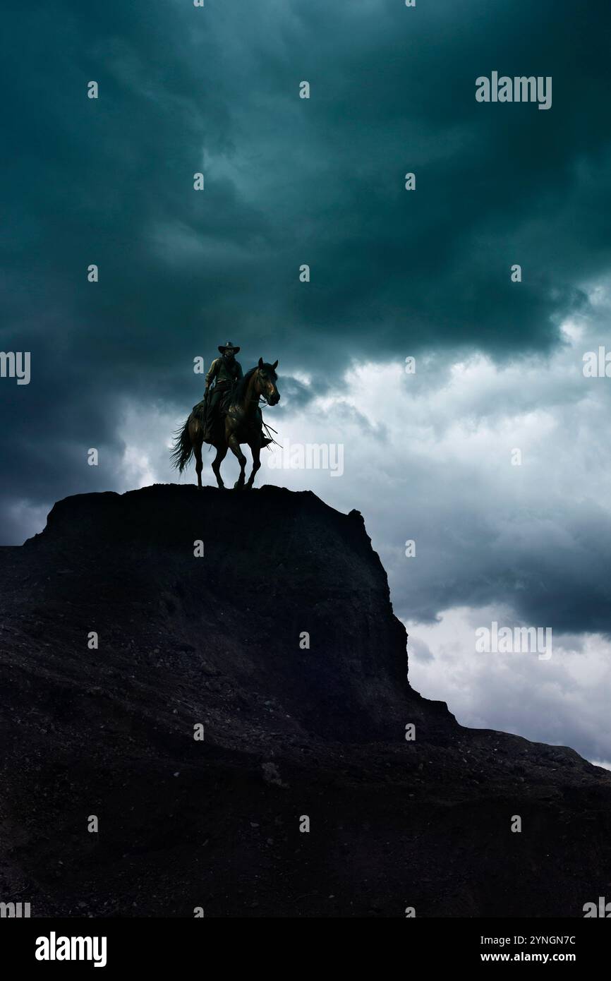 Silhouette eines Cowboys auf einem Pferd, der auf einer Klippe steht, dramatischer Himmel Hintergrund Stockfoto