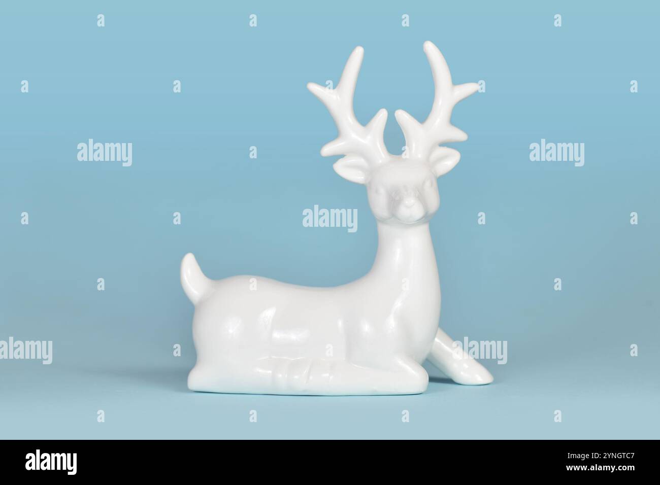 Weiße keramische Weihnachts- oder Winterdekoration Hirschfigur auf hellblauem Hintergrund Stockfoto