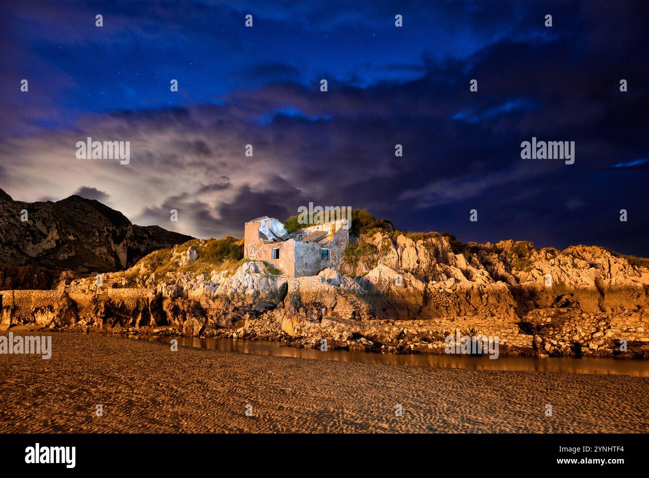 Lange Exposition einer Felsmauer mit antiker Konstruktion in einem kleinen See in der Abenddämmerung mit auffälliger Farbe Stockfoto
