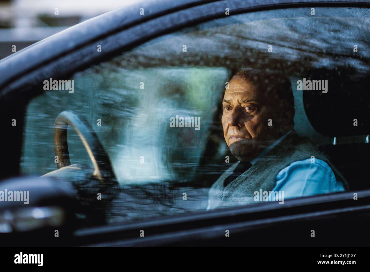 Ein Senior sitzt in einem geparkten Auto und blickt nachdenklich aus dem Fenster. Die ruhige Umgebung draußen steht im Kontrast zu seinem kontemplativen Ausdruck d Stockfoto