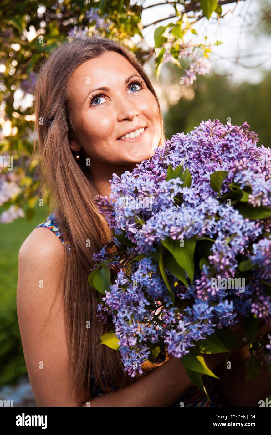 Mode junge Frau mit Fliederblumen im Garten Stockfoto