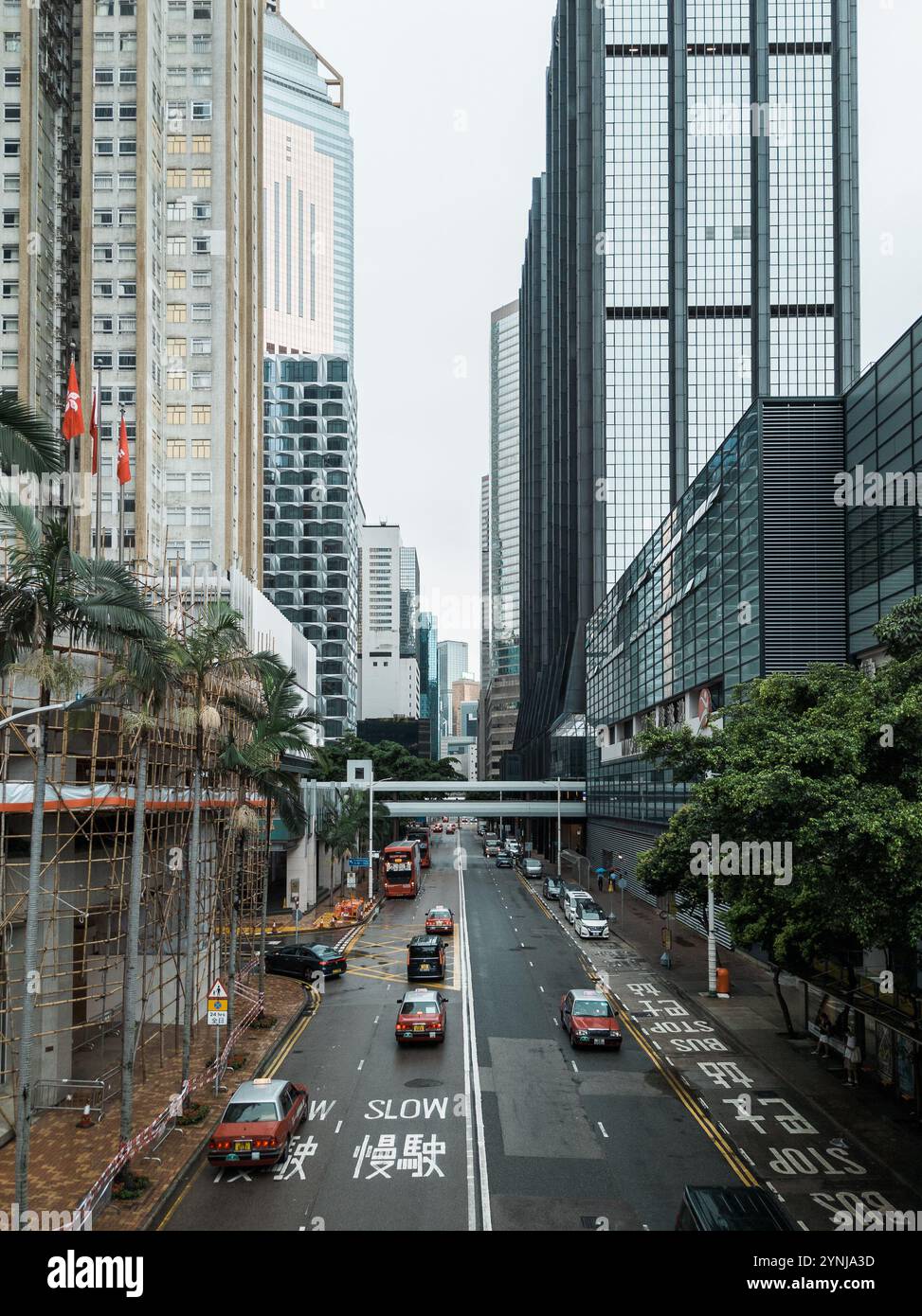 Moderne urbane Straßenszene mit Hochhäusern, Verkehr und roten Doppeldeckerbussen inmitten einer pulsierenden Stadtlandschaft. Stockfoto