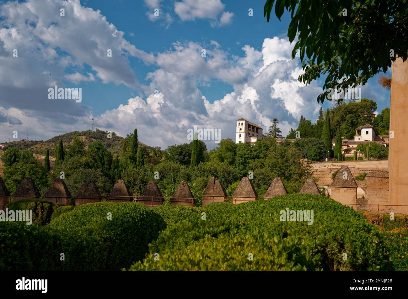 Üppige Gärten und der berühmte weiße Turm des Generalife in der Alhambra von Granada, unter einem lebendigen Himmel Stockfoto