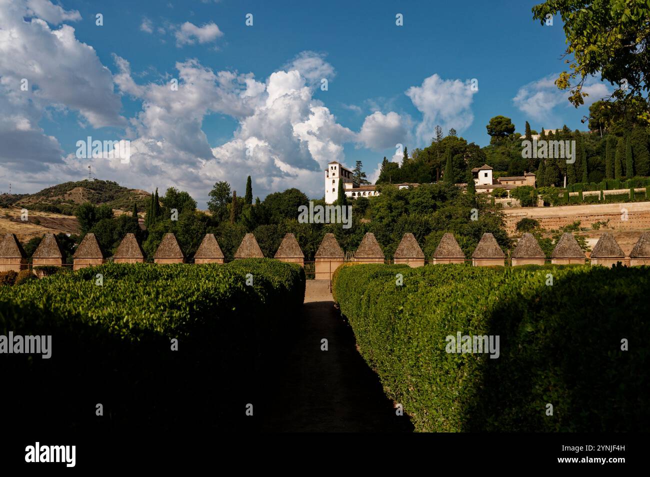 Üppige Gärten und der weiße Turm des Generalife in der Alhambra von Granada unter einem leuchtend blauen Himmel Stockfoto