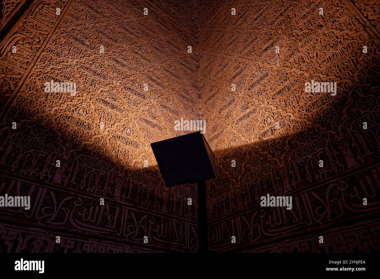 Komplexe arabische Kalligraphie, beleuchtet durch sanftes Licht in den Nasridenpalästen, Alhambra von Granada Stockfoto