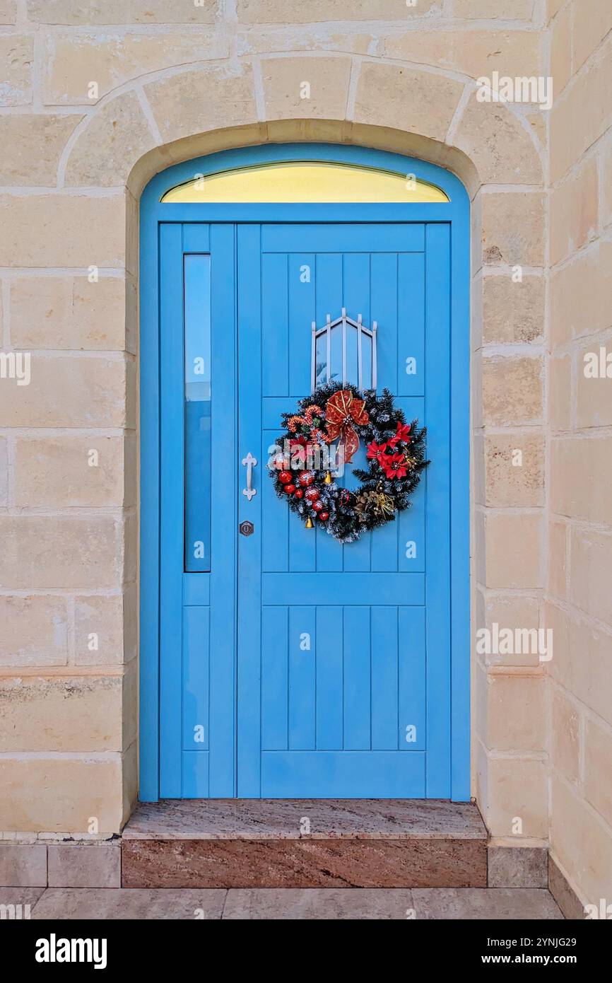 Lebendige blaue Tür mit festlichem Weihnachtskranz Stockfoto