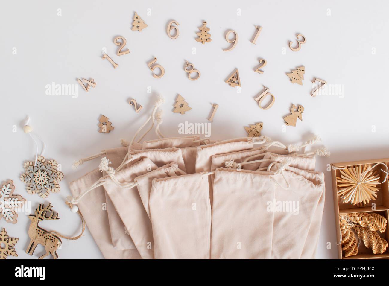 Weihnachts-Adventskalender mit Samtbeuteln und hölzernen Zahlen auf weißem Hintergrund. Stockfoto