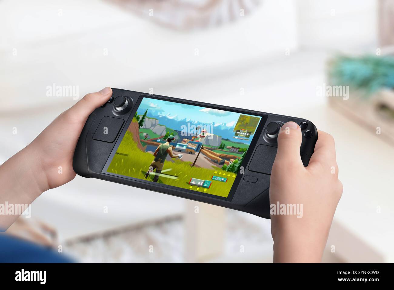 Kind, das eine Handheld-Spielkonsole hält und ein Actionspiel anzeigt. Wohnzimmer Hintergrund. Neuerungen im Bereich des Marktwachstums für Handheld-Konsolen a Stockfoto