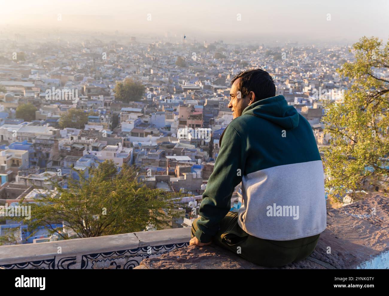 Junger Mann mit Blick auf die überfüllte Stadt am Morgen vom Berggipfel Stockfoto