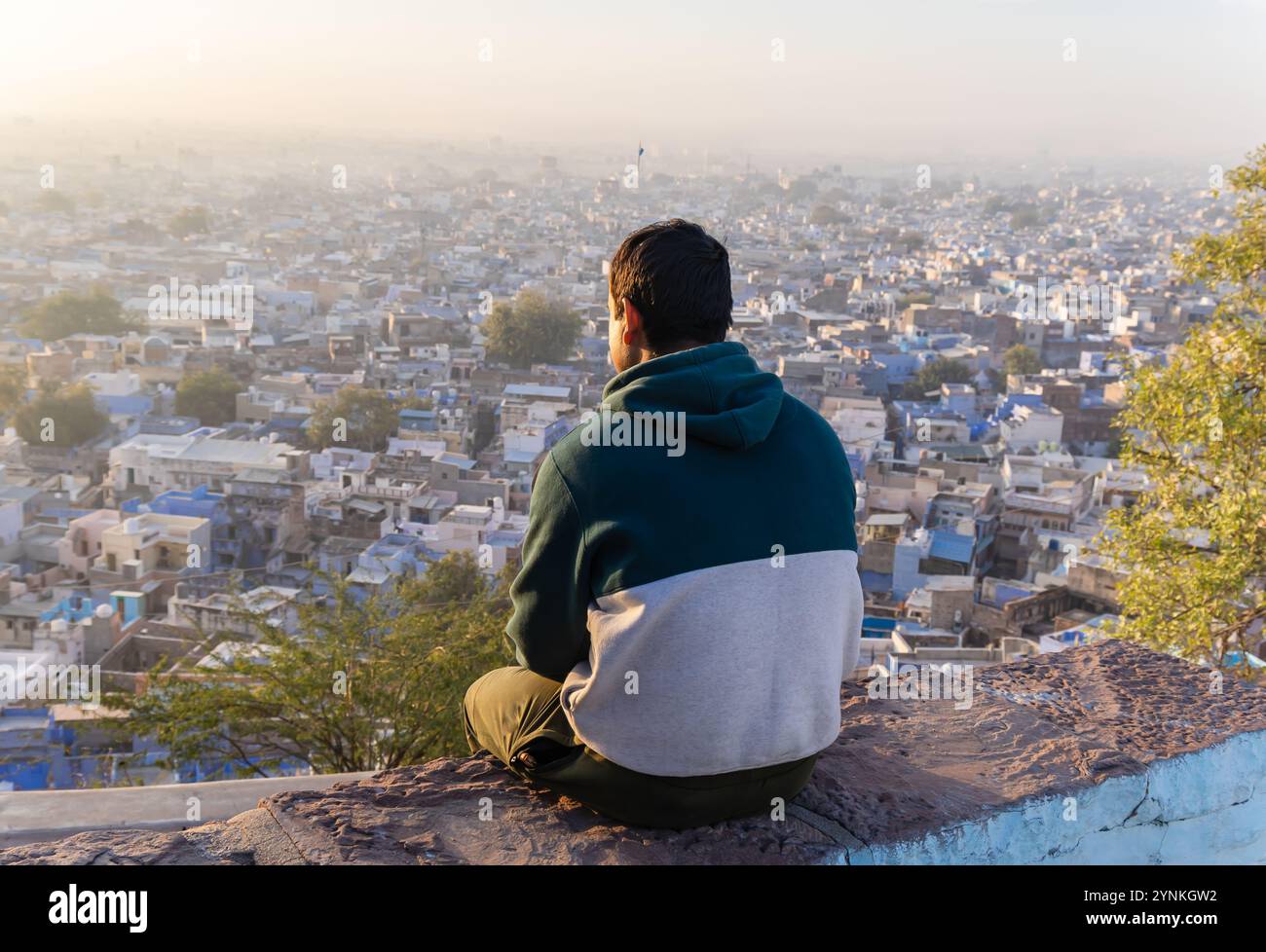 Junger Mann mit Blick auf die überfüllte Stadt am Morgen vom Berggipfel Stockfoto