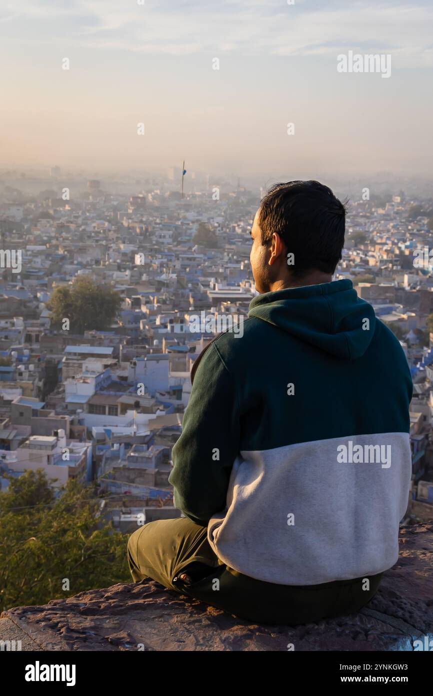 Junger Mann mit Blick auf die überfüllte Stadt am Morgen vom Berggipfel Stockfoto