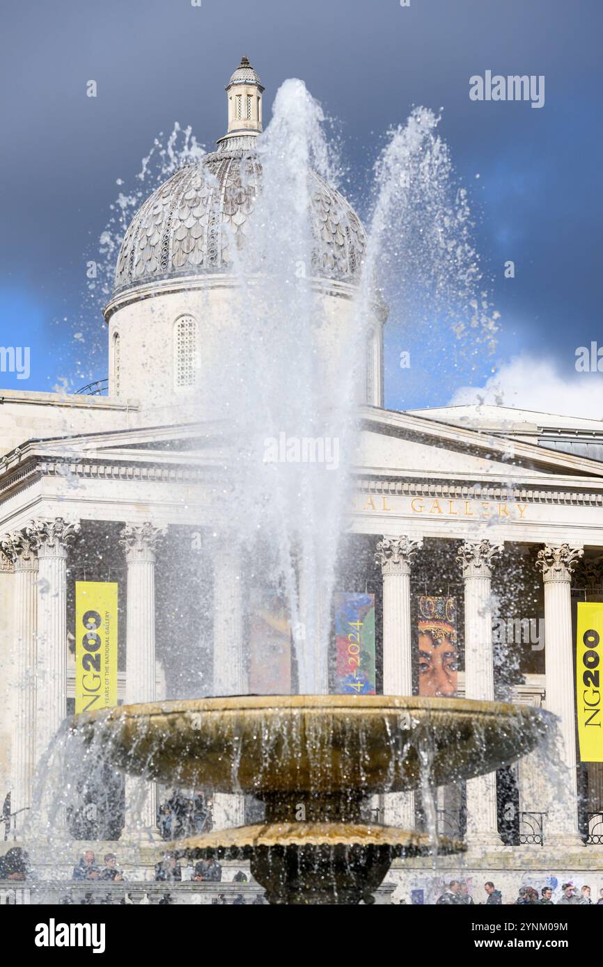 Einer der Springbrunnen am Trafalgar Square mit der National Gallery im Hintergrund. Trafalgar Square, London, Großbritannien. Oktober 2024 Stockfoto