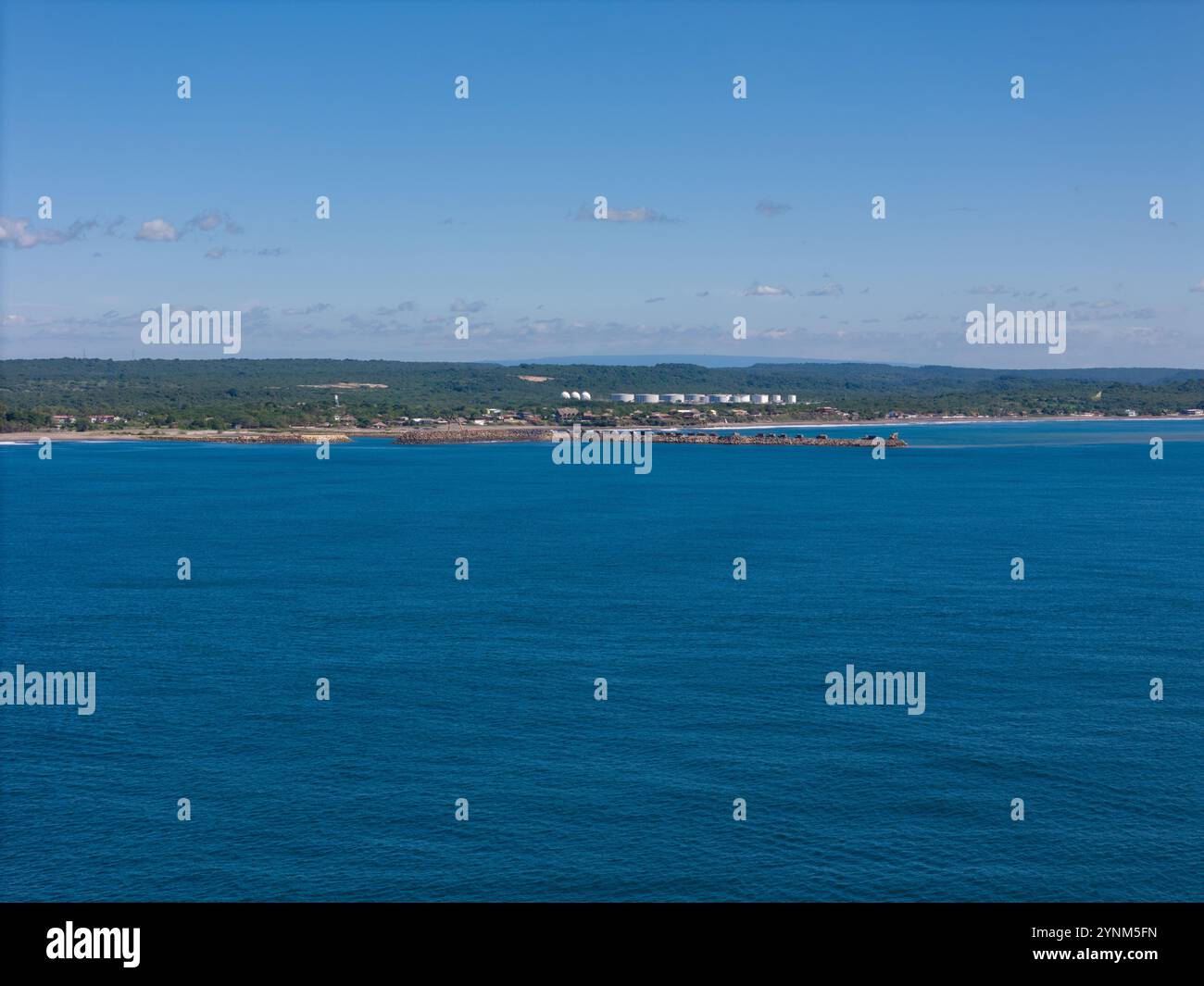 Die friedliche Küste erstreckt sich entlang der Küste, umgeben von grünen Hügeln und klarem blauem Himmel, lädt zum Entspannen ein. Stockfoto