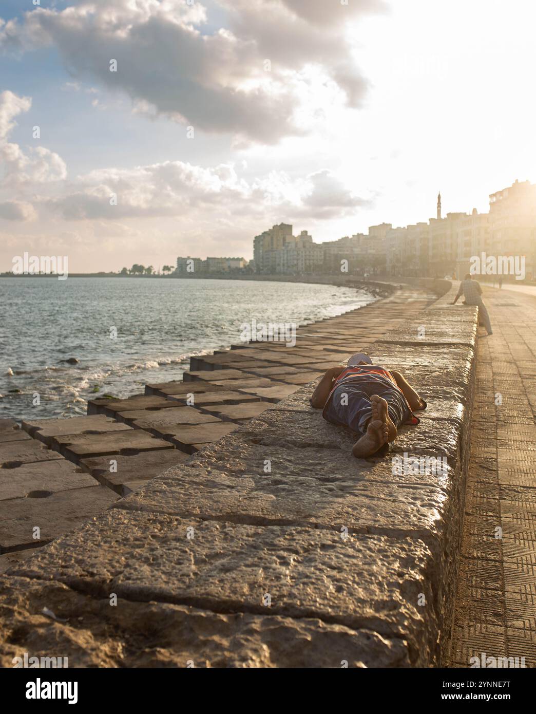 Ein Mann, der ein Nickerchen auf der Corniche in Alexandria macht Stockfoto