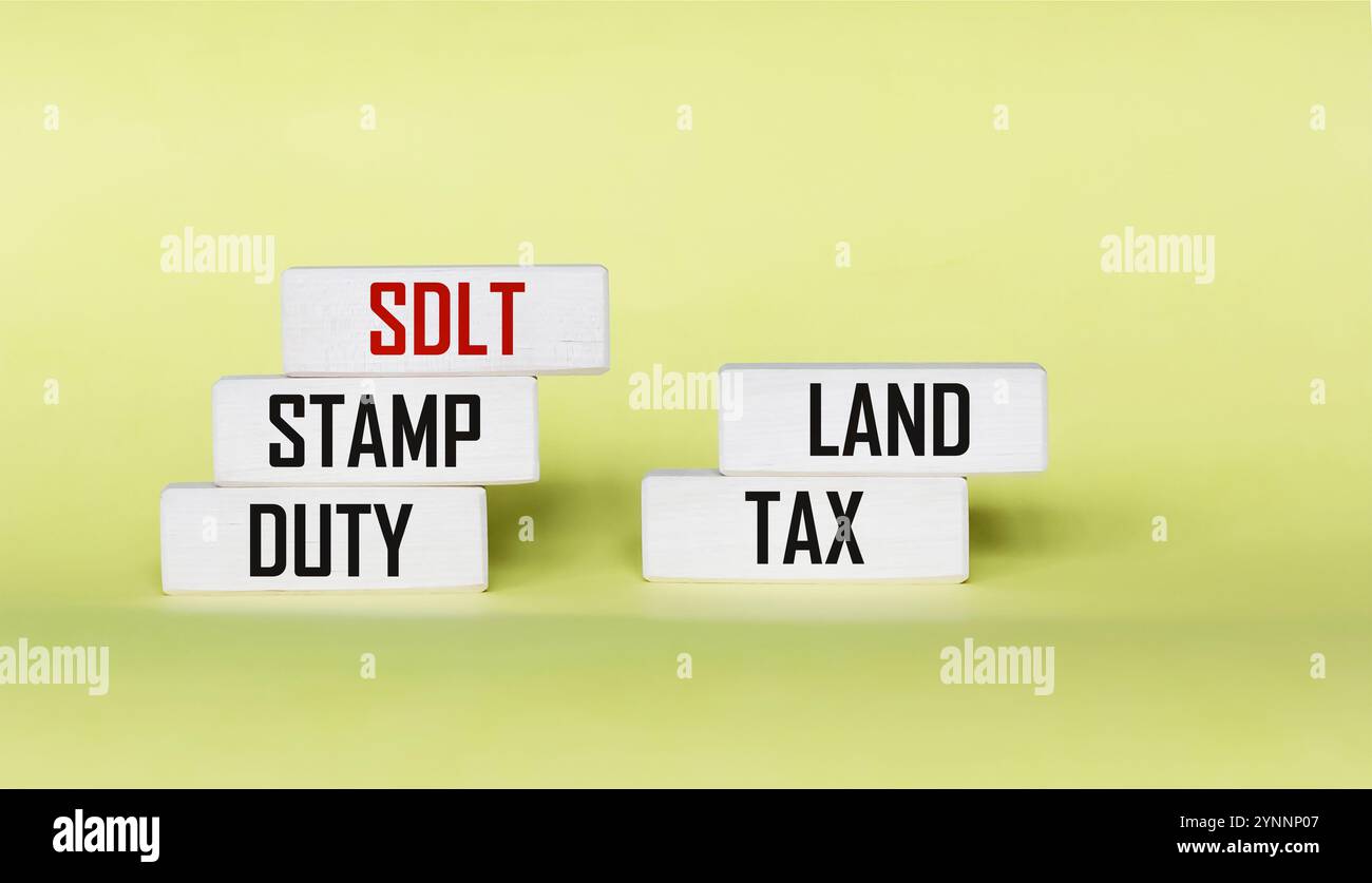 SDLT - Stempelsteuer, Landsteuer, geschrieben auf Blöcken auf gelbem Hintergrund. Stockfoto