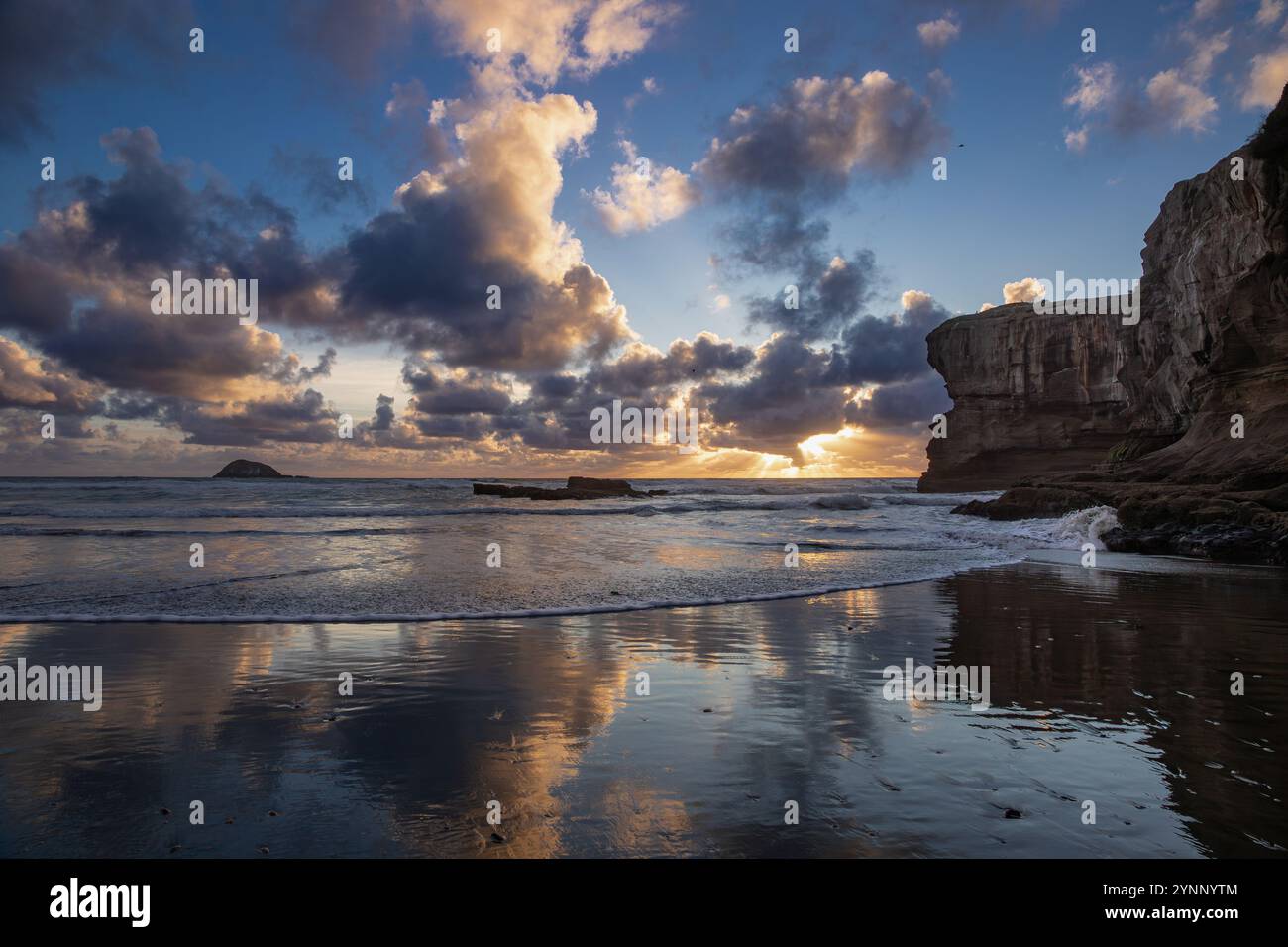 Ätherischer Moment des Muriwai Strandes bedeckt mit Wolken bei Sonnenuntergang Stockfoto