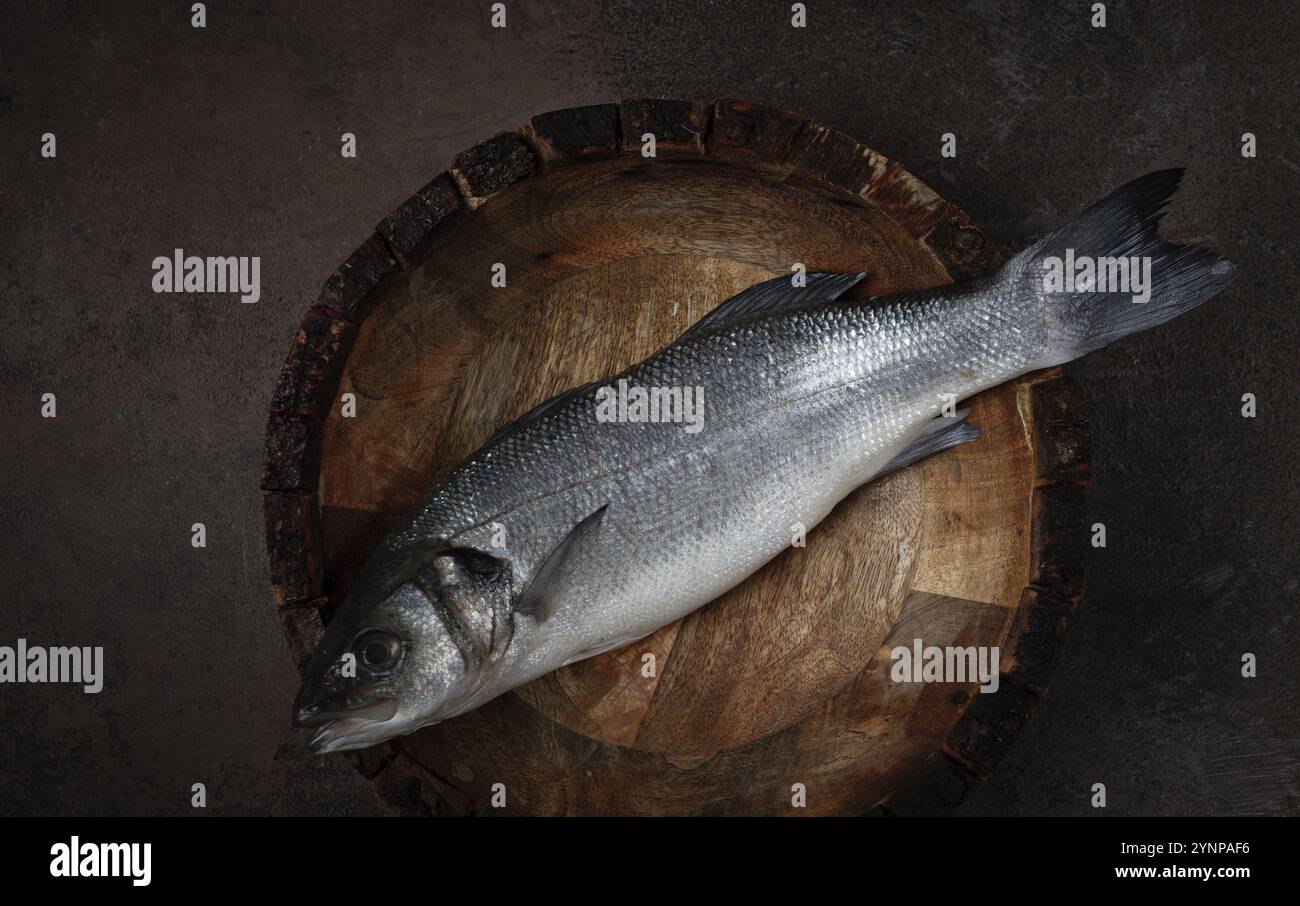 Frischer, roher Wolfsbarsch Fisch, auf einem Holzteller, Blick von oben, keine Leute. Stockfoto