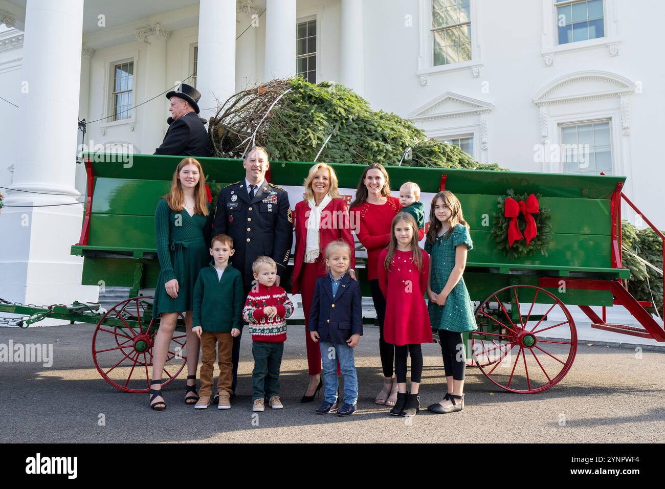 Washington, Usa. November 2024. U. S First Lady Jill Biden, Mitte, posiert mit einer Militärfamilie vor dem Weihnachtsbaum des Weißen Hauses, als er mit einem Pferdewagen ankommt. Während der jährlichen Zeremonie am 25. November 2024 im North Portico des Weißen Hauses in Washington, DC, stammt die 20 Fuß lange Fraser-Tanne von Cartner's Christmas Tree Farm in den Bergen von North Carolina. Quelle: Oliver Contreras/White House Photo/Alamy Live News Stockfoto
