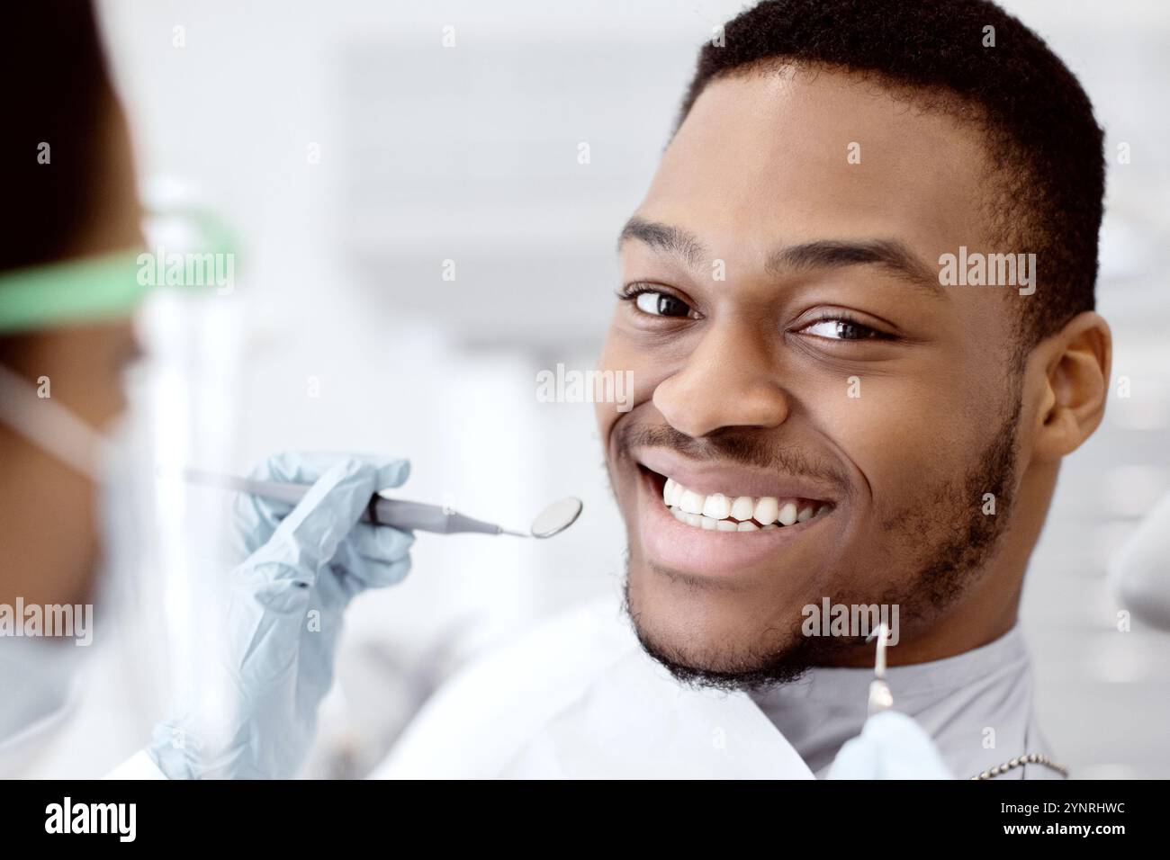 Gutaussehender, Lächelnder Schwarzer, Der Während Der Medizinischen Untersuchung Auf Dem Zahnarztstuhl Sitzt Stockfoto