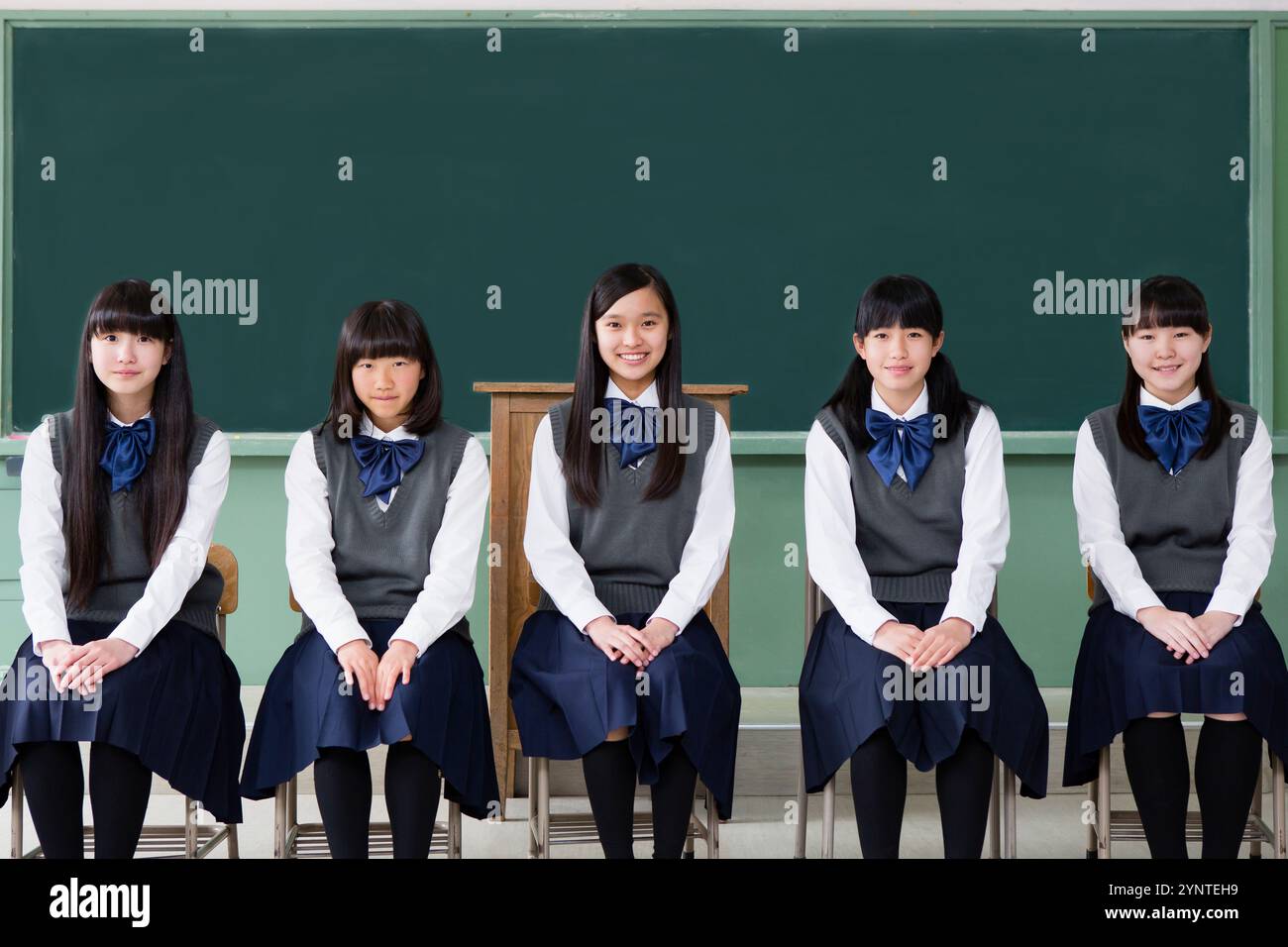 Studentin sitzt auf einem Stuhl in einer Reihe in einem Klassenzimmer Stockfoto
